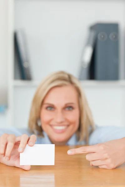 Mujer de negocios señalando una tarjeta agachada detrás de su escritorio —  Fotos de Stock