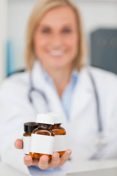 Sorrindo loira médico segurando medicina — Fotografia de Stock