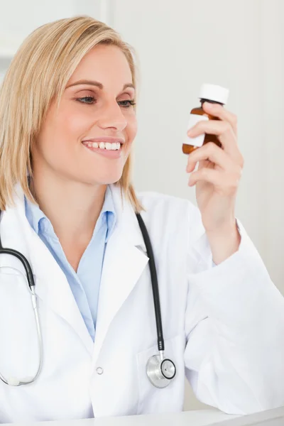 Usměvavá blondýnka doktor při pohledu na medicínu — Stock fotografie