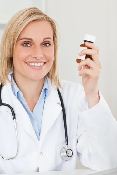 Sarışın doktor ilaç kameraya benziyor tutan gülümseyerek — Stok fotoğraf
