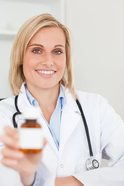 Uśmiechnięta blondynka lekarz trzymając medycyny do aparatu — Zdjęcie stockowe
