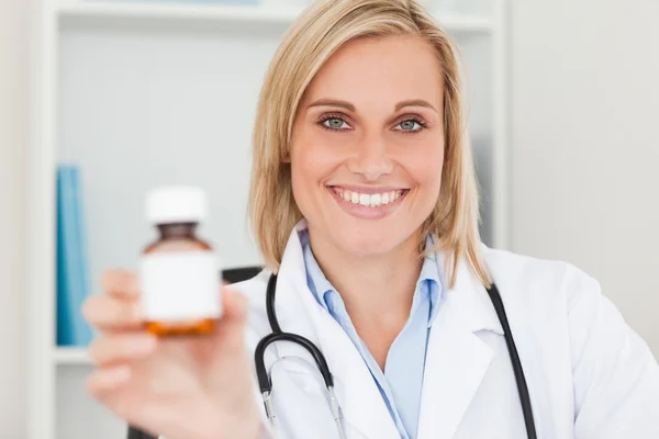 Prachtvolle blonde Ärztin hält Medikamente in die Kamera — Stockfoto