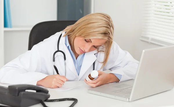 Lekarz pisze coś w dół trzymając medycyny — Zdjęcie stockowe