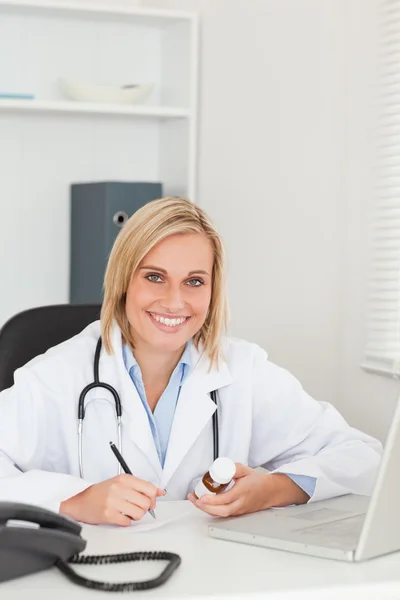 Médico escribiendo algo mientras sostiene la medicina mira en —  Fotos de Stock