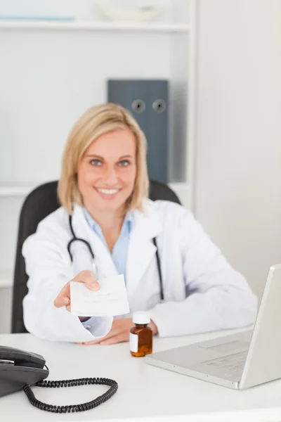 Sonriente médico sosteniendo prescripción mira en la cámara — Foto de Stock
