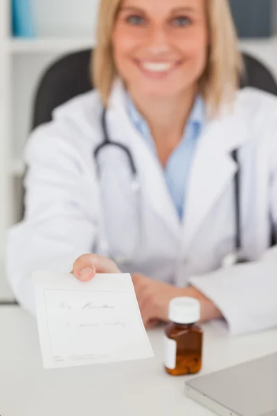 Médico sorrindo dando prescrição olha para a câmera — Fotografia de Stock