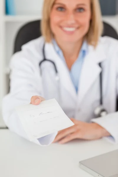 Sonriente médico rubio dando prescripción mira en la cámara — Foto de Stock