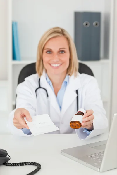 Uśmiechający się blondynka lekarz posiadający recepty i medycyna wygląda — Zdjęcie stockowe