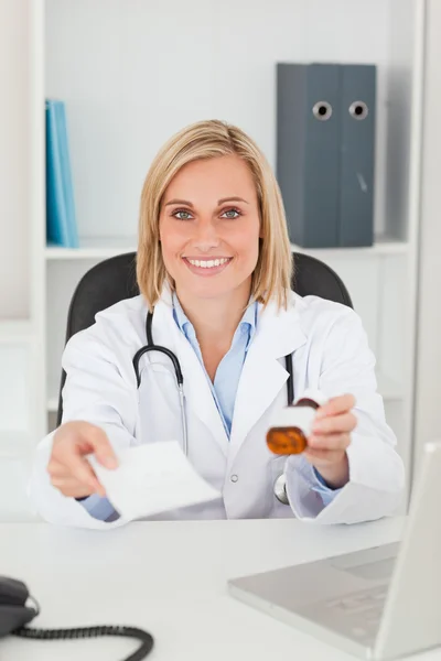 Médico loiro encantador segurando prescrição e sorrisos de medicina — Fotografia de Stock
