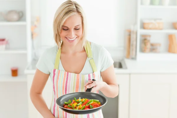 Женщина смотрит на сковороду, наполненную перцем — стоковое фото