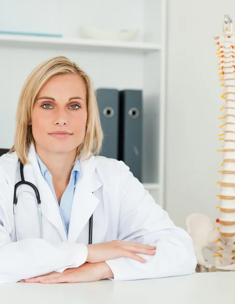 Allvarliga läkare med modell ryggraden bredvid henne ser in i kameran — Stockfoto
