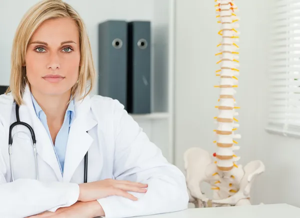 Allvarliga blond läkare med modell ryggraden bredvid henne ser in ca — Stockfoto