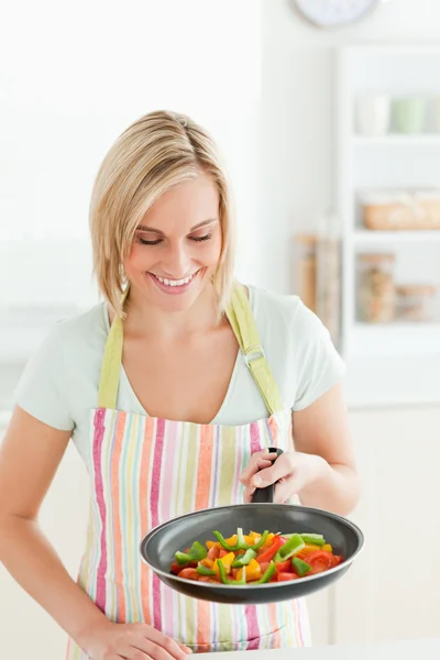 Leuke vrouw kijken naar pan gevuld met paprika 's — Stockfoto