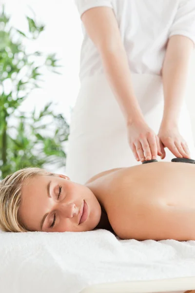 Blondine entspannt sich während Steintherapie auf einer Massageliege — Stockfoto
