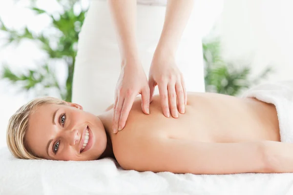 Bionda donna sorridente rilassante su un lettino durante il massaggio — Foto Stock