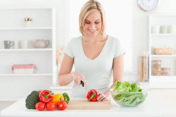 Uśmiechnięta kobieta krojąca warzywa — Zdjęcie stockowe
