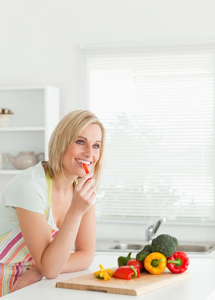 Portrait of a young woman eating red peppers — Stock Photo, Image