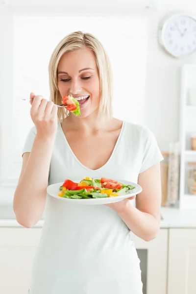 Retrato de una mujer rubia disfrutando de ensalada mixta — Foto de Stock