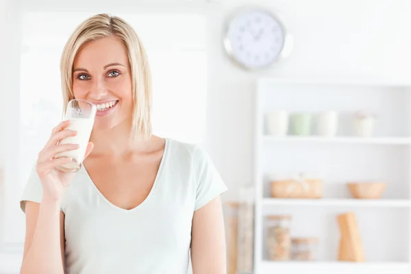 Kobieta pije mleko patrzy w kamerę. — Zdjęcie stockowe