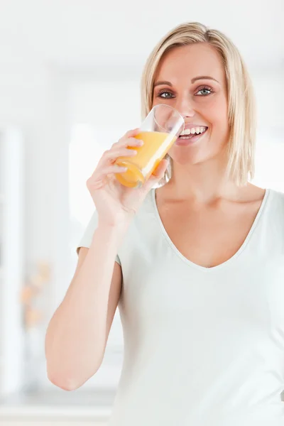 Ładny kobieta pije sok pomarańczowy, patrząc na kamery — Zdjęcie stockowe