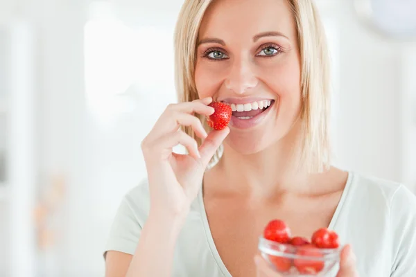 Nahaufnahme einer Frau, die Erdbeeren isst und in die Kamera schaut — Stockfoto