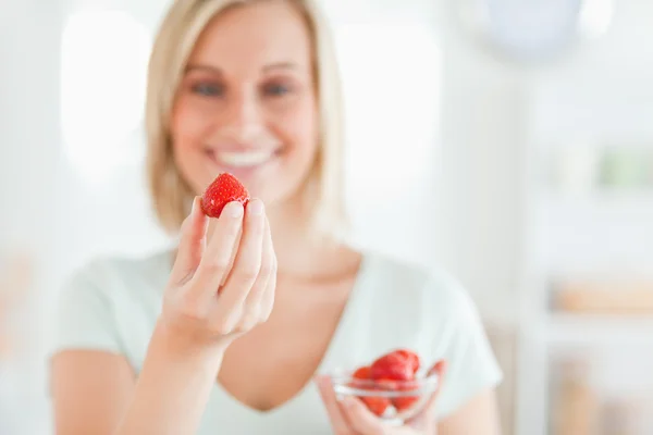 Primer plano de una mujer joven disfrutando de comer fresas mirando i — Foto de Stock