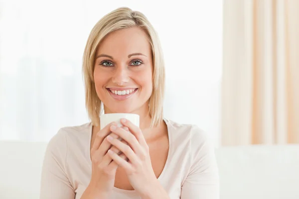Χαμογελαστή γυναίκα κρατώντας ένα φλιτζάνι καφέ — Φωτογραφία Αρχείου