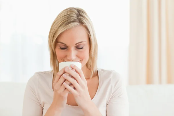 Smiling woman smelling her cup of coffee — Stock Photo, Image