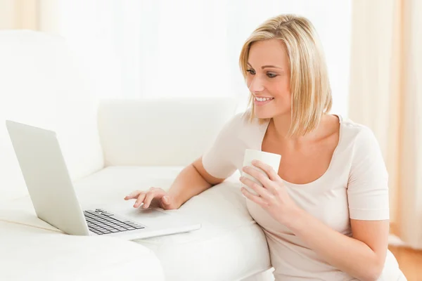 Donna che tiene una tazza durante l'utilizzo di un computer portatile — Foto Stock