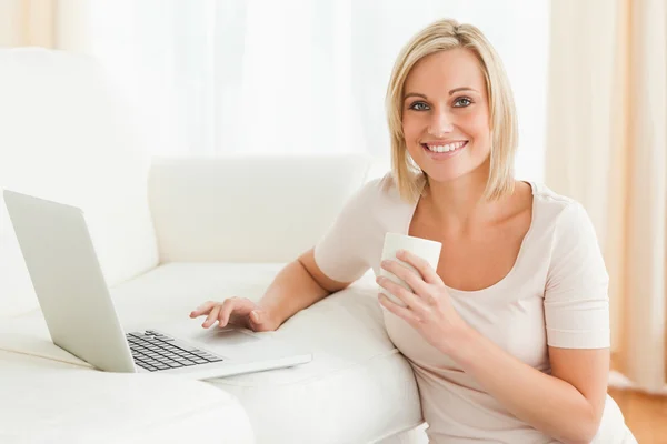Kvinna med en mugg medan med en bärbar dator — Stockfoto