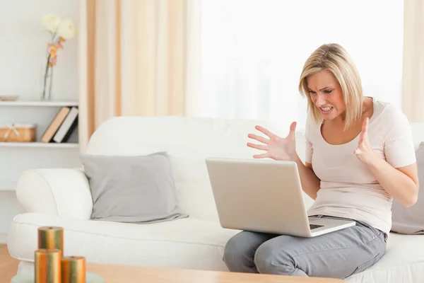 Närbild av en upprörd blond kvinna som använder en bärbar dator — Stockfoto