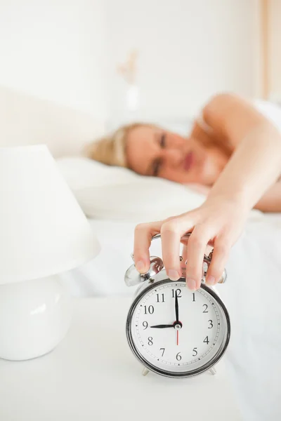 Portrait of a woman switching off her alarm clock — Stock Photo, Image