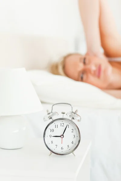 Portrait of an upset woman awaked by her alarm clock — Stock Photo, Image