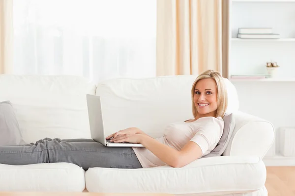 女人躺在一张沙发上，一台笔记本电脑 — 图库照片