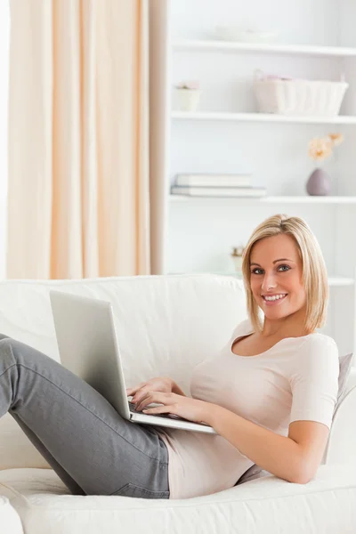 ノート パソコンとソファーに横たわってかわいい女性の肖像画 — ストック写真