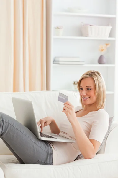 Portrait of a woman buying online whilie lying on a couch — Stock Photo, Image
