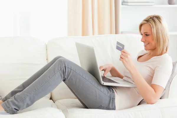 Mulher comprando online whilie deitado em um sofá — Fotografia de Stock