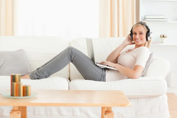 Blond-haired woman with a laptop and headphones — Stock Photo, Image