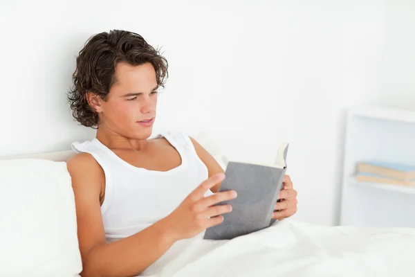 Homme aux cheveux bruns lisant un livre — Photo