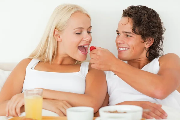 Handsome man giving a strawberry to his girlfriend — Stock Photo, Image