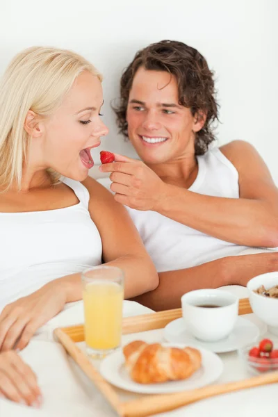 Retrato de homem bonito dando um morango para sua namorada — Fotografia de Stock