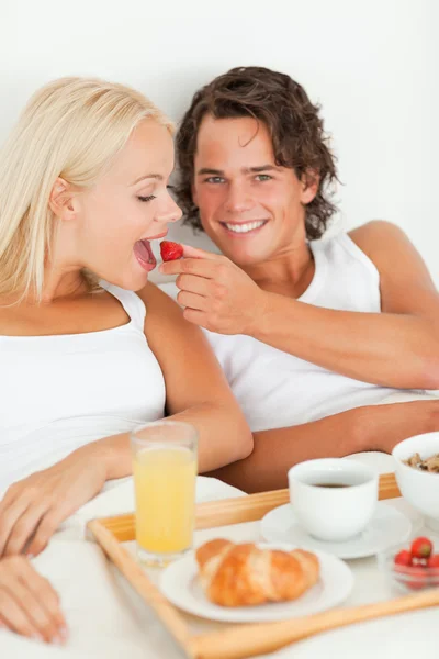 彼のガール フレンドにイチゴを与える笑みを浮かべて男の肖像 — ストック写真