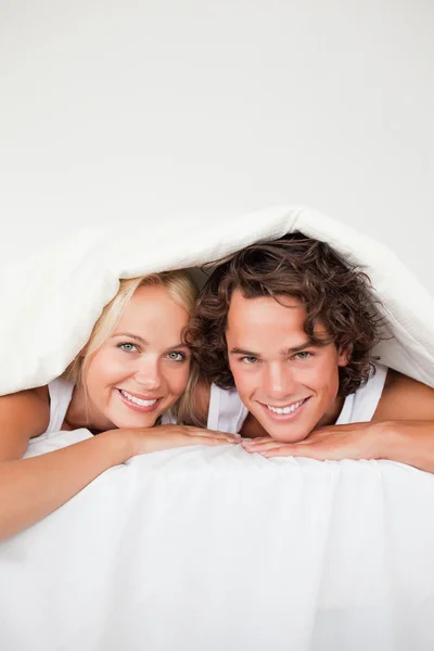 Ritratto di una coppia sorridente sotto un piumone — Foto Stock