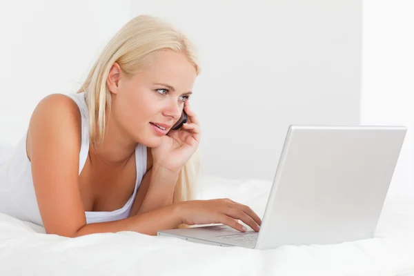Sarışın kadın bir dizüstü bilgisayar kullanarak telefon — Stok fotoğraf