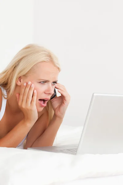 Портрет засмученої жінки на телефоні під час використання ноутбука — стокове фото