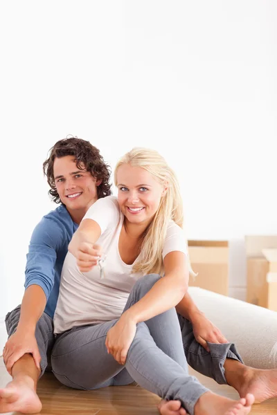 Portrait of a cute woman sitting with her boyfriend giving keys — Stock Photo, Image