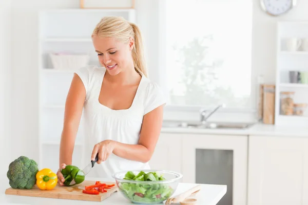 Blond-haired woman slicing pepper — Stock Photo, Image