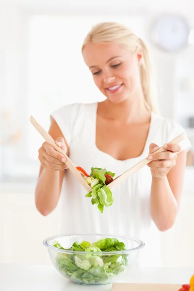 Porträt einer blonden Frau, die einen Salat mixt — Stockfoto