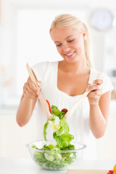 Retrato de una mujer sonriente mezclando una ensalada — Foto de Stock