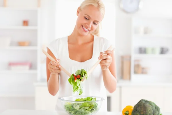 Glimlachende vrouw die een salade mengt — Stockfoto